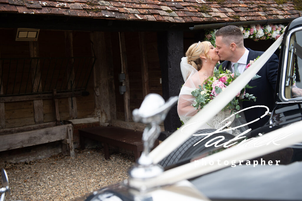 bride and groom kissing, exterior barn, rolls royce foreground