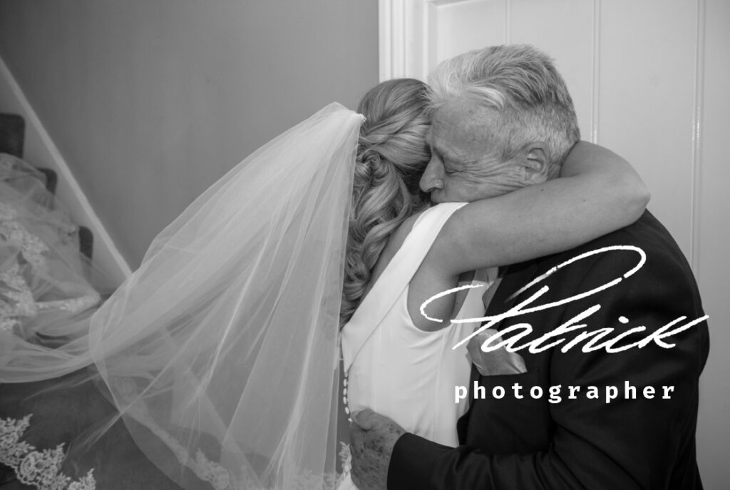 bride cuddling emotional dad at foot of stairs.