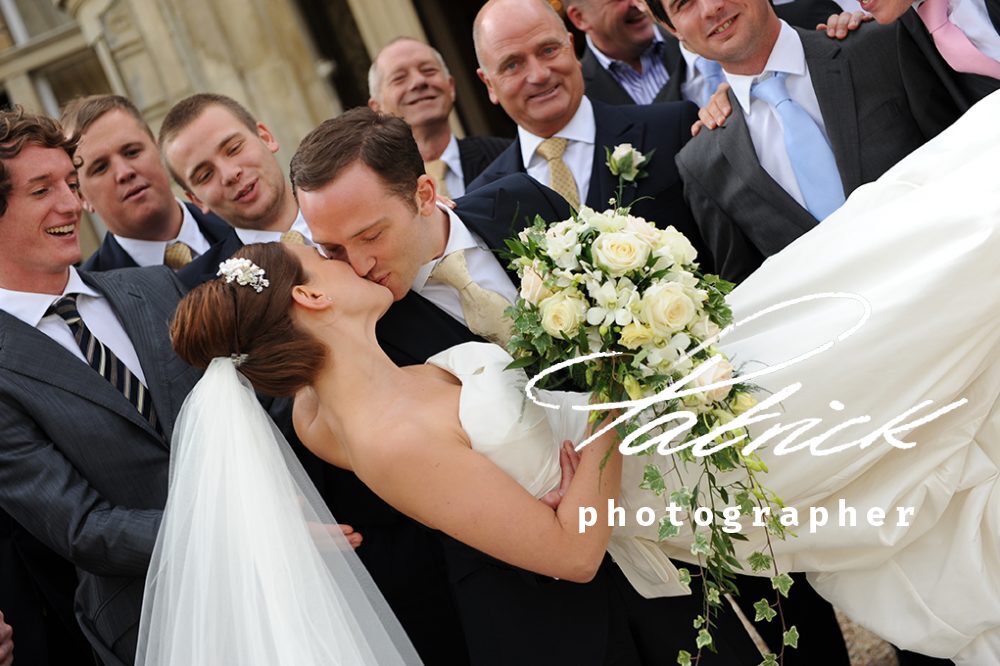 groom kissing bride, bouquet, groomsmen