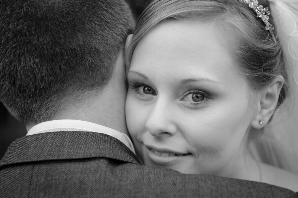 bride looks at camera, over groom shoulder, black and white