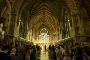 aisle view, st albans abbey, interior, candlelit, low lighting, guests in pews, bride and groom at altar