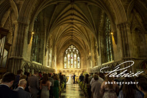 aisle view, st albans abbey, interior, candlelit, low lighting, guests in pews, bride and groom at altar