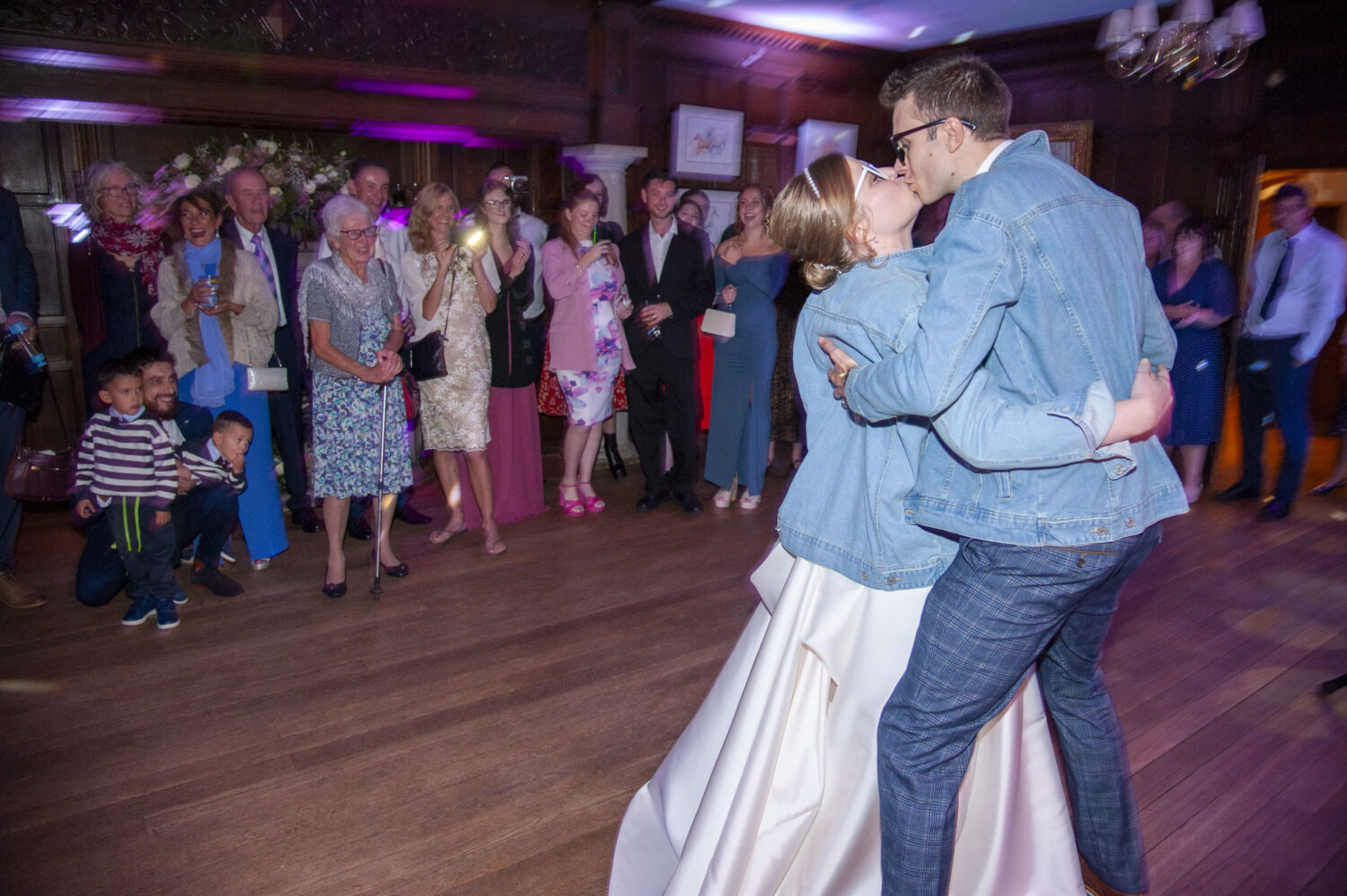 landwades hall, great hall, bride and groom first dance, denim jacket, heart shape sun shades, party, bride and groom kissing, arms wrapped, onlookers