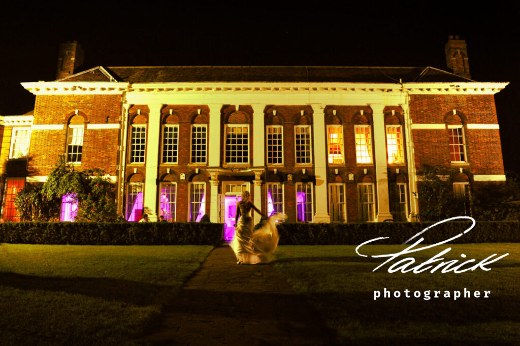 luxurious Manor House at night, atmospheric, bride walks away from camera towards building. Wedding dress, blonde bride