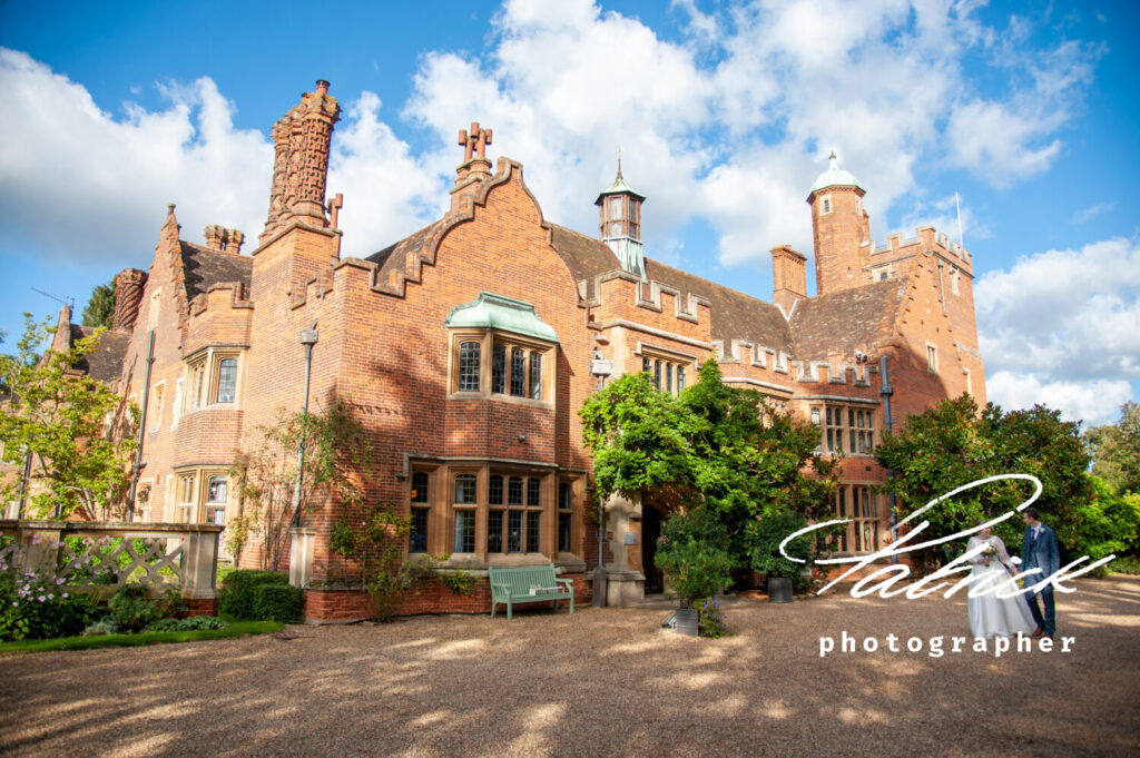 bride and groom walk hand in hand, front of lanwades hall