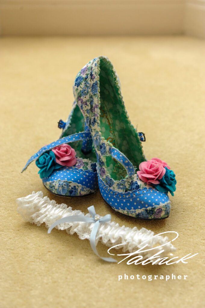 Irregular Choice style shoe. Blue and white dotted material. Green pattern lining. Kitten heel. Mid heel classic heel. Blue and pink roses. Buckle. White garter, blue ribbon set with pearls.