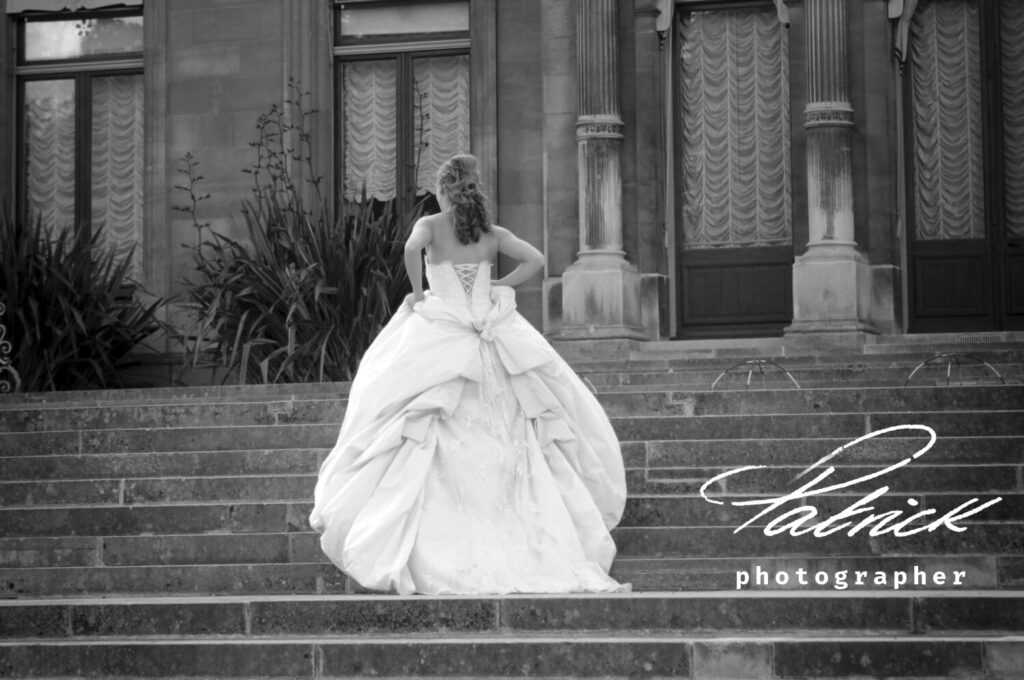 black and white image, posterior shot bride walking away up stairs towards stately waddesdon manor