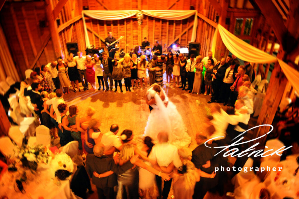 interior tewinbury hotel, barn, band, guests circle heart shape, bride and groom dancing, elevated shot, blurred