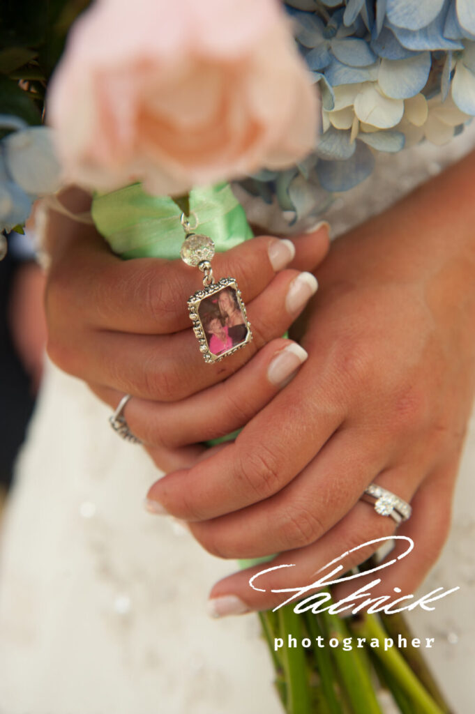 close up hands, holding veil. keepsake photograph in wedding bouquet charm. bride wears engagement and wedding ring