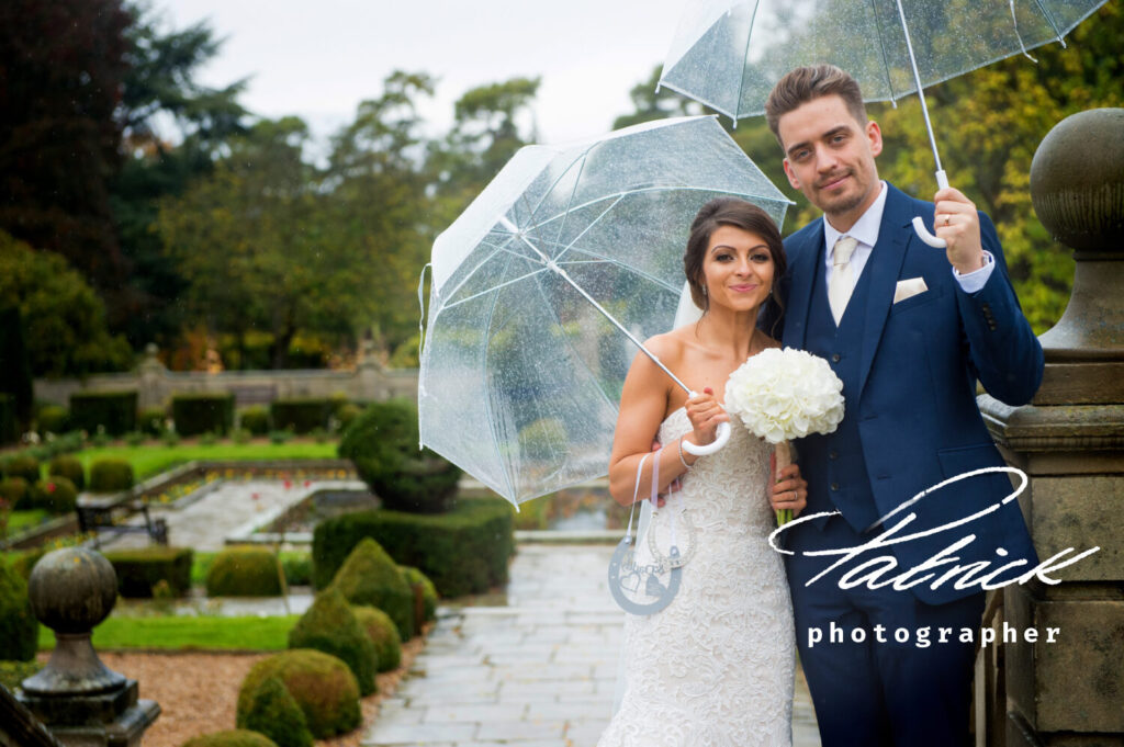 fanhams hall gardens, paved areas, rain, umbrellas, bride and groom facing camera