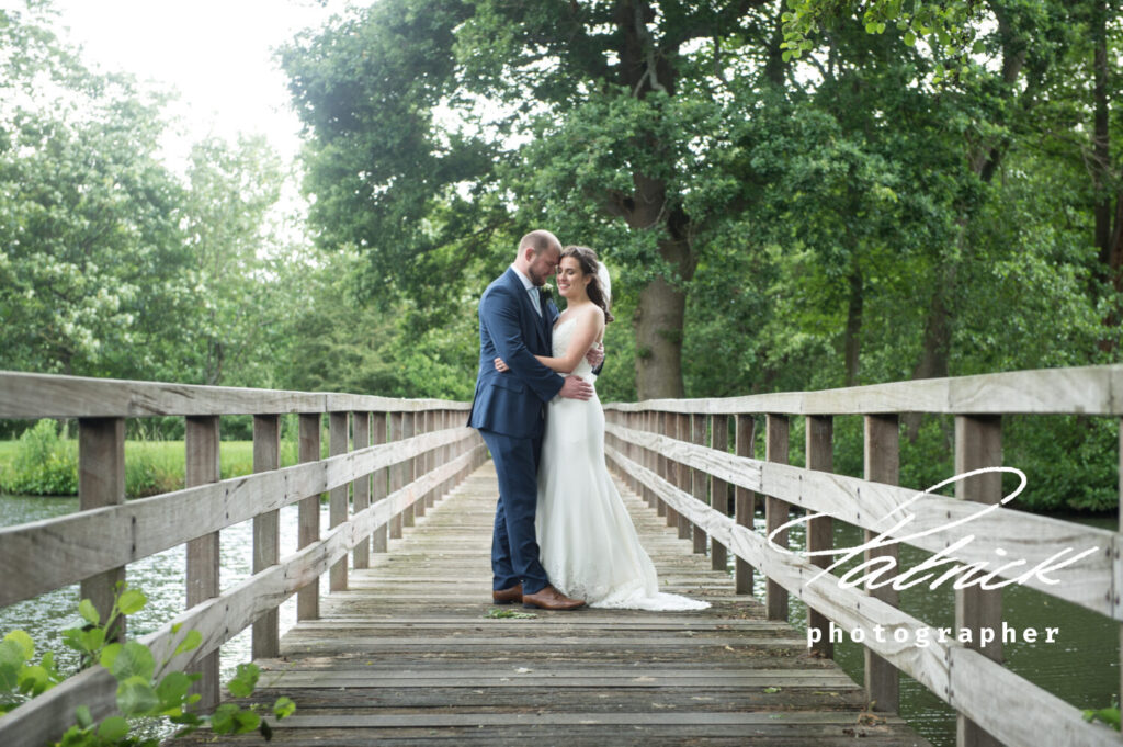 bride and groom at Hertford Castle grounds wooden bridge river trees