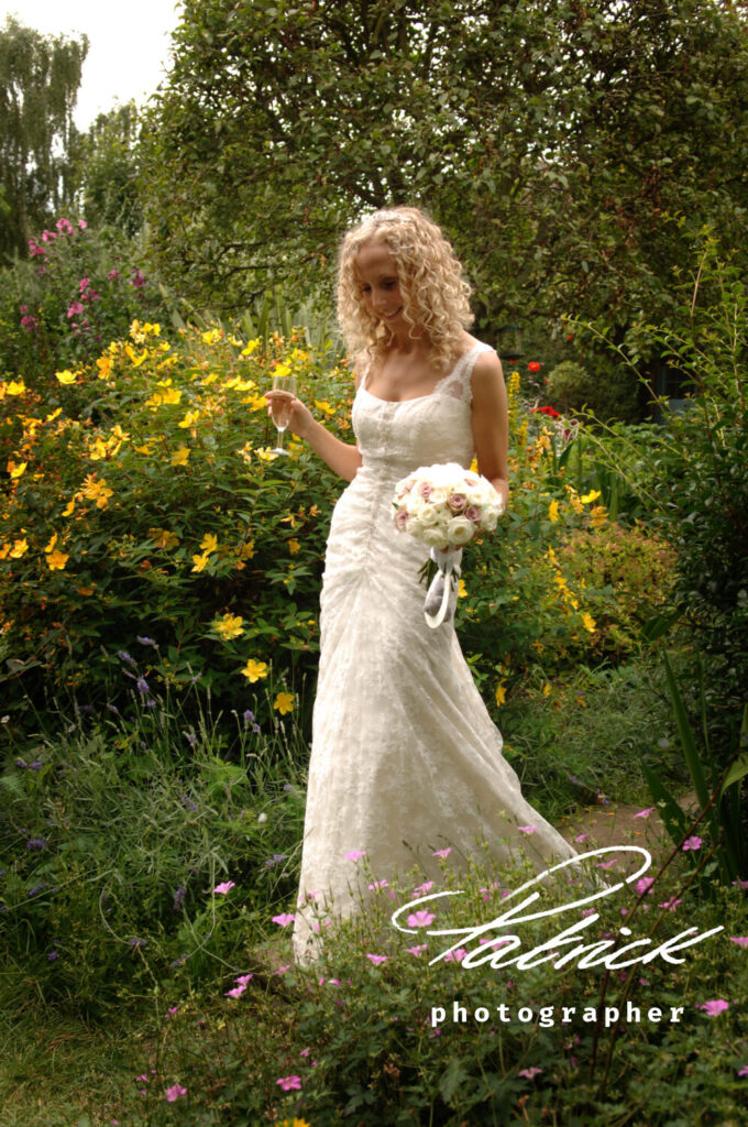 south farm bride, Emma, walking through garden, yellow flowers, blond curls, holds white pink bouquet, champagne