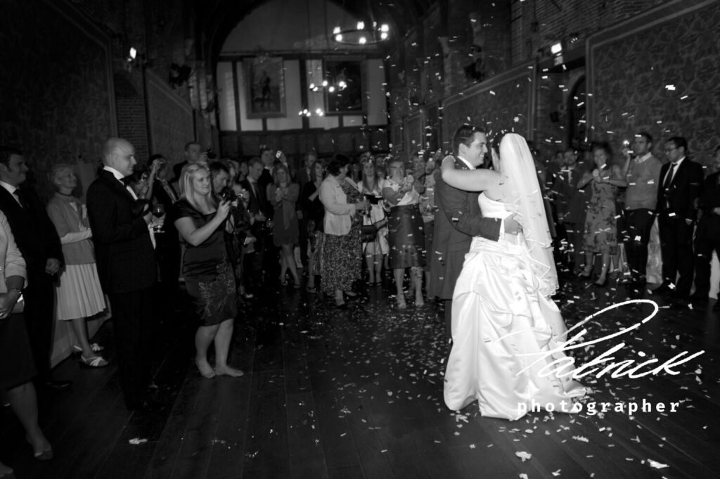 black and white image, interior Old Palace, Hatfield House. Bride and Groom first dance. Confetti. Guests watching