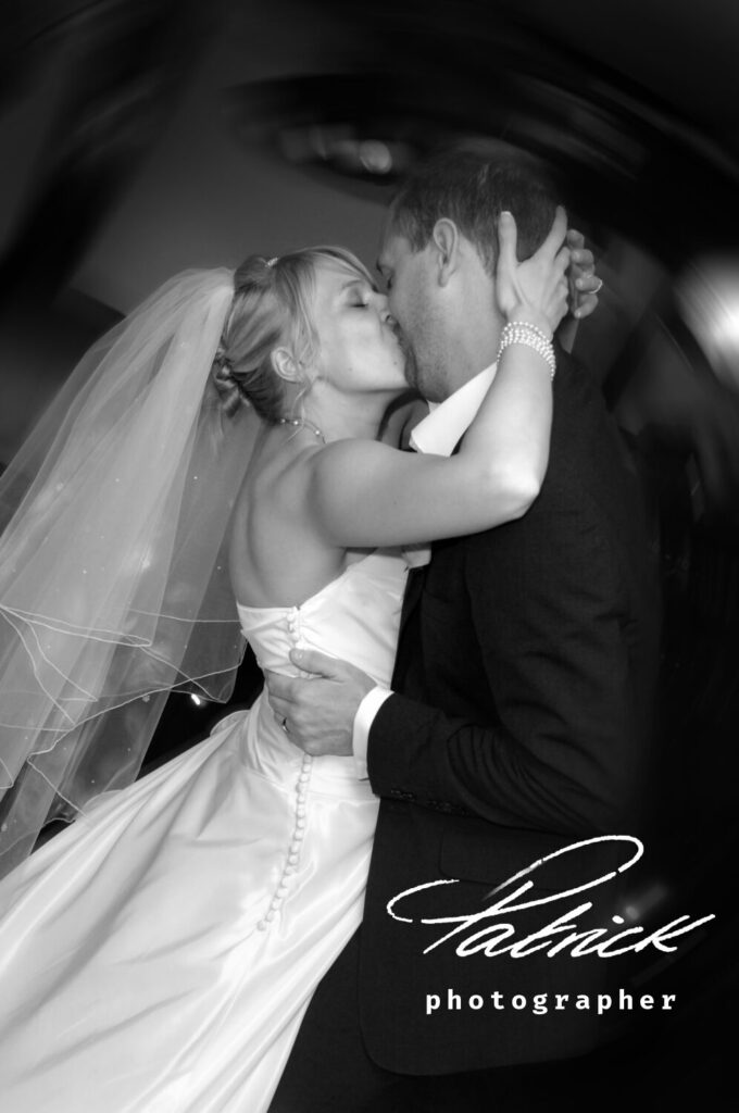 black and white image, bride kisses groom passionately, night shot, party