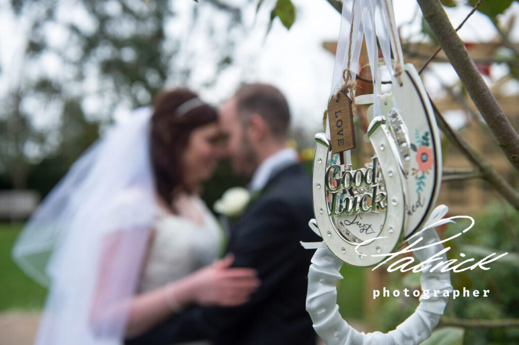 good luck charms foreground, blurred bride and groom background ami and Phil Randall