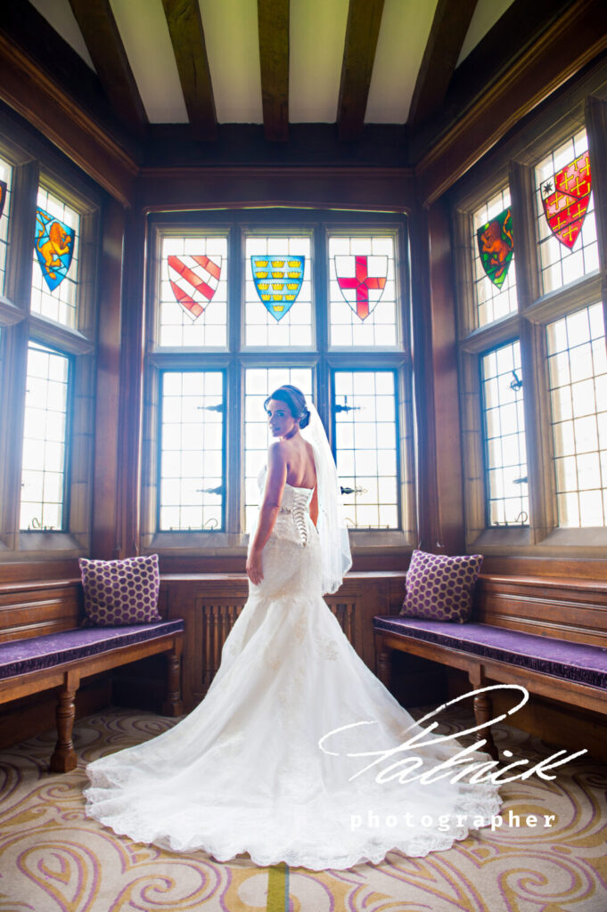 stained glass windows, overlooking gardens at Fanhams Hall. bride Looking over her shoulder, wearing full length bridal gown