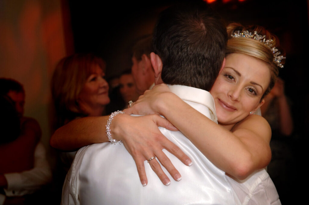 bride hugs her new husband as they embrace for their first dance