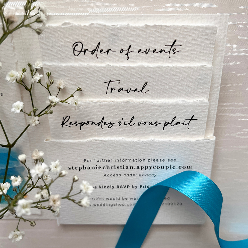 wedding stationery, detail shot, flowers and blue ribbon foreground, written in french