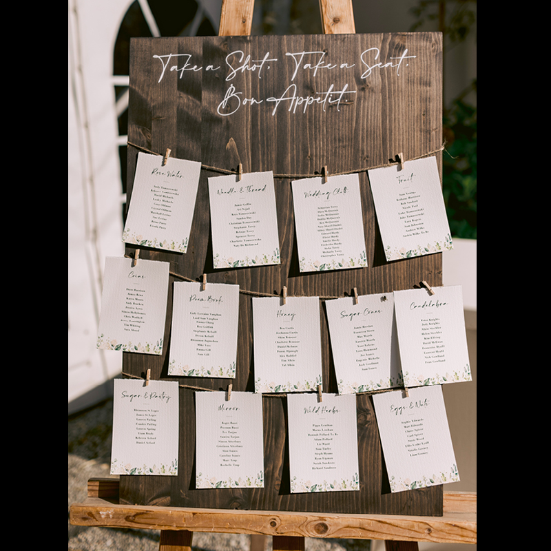 wedding table names displayed on pegs in three lines on a wooden board