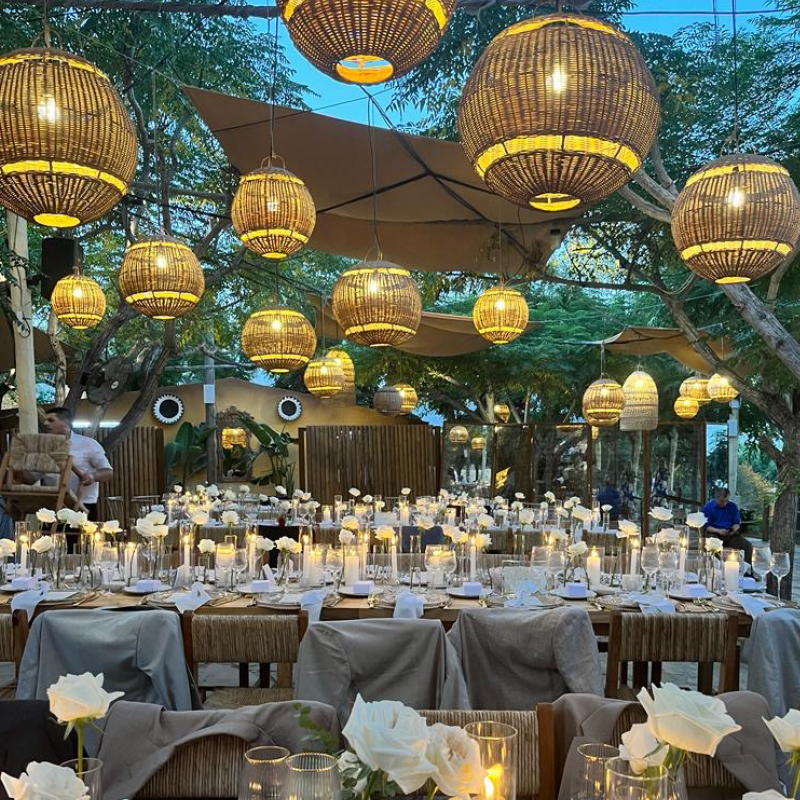 room set showing gold and turquoise ceiling lanterns, candlelit dressed tables adorned with bespoke wedding stationery