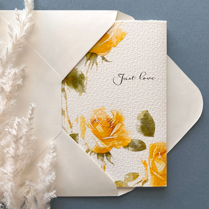 partly exposed wedding stationery revealed from opened wedding envelope with words Just Love showing, decorated with feathers