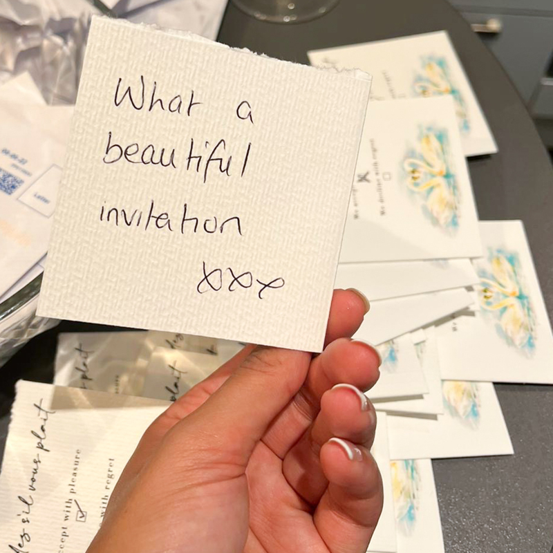 close up hand written 'what a beautiful invitation, hand held, wedding stationery in background