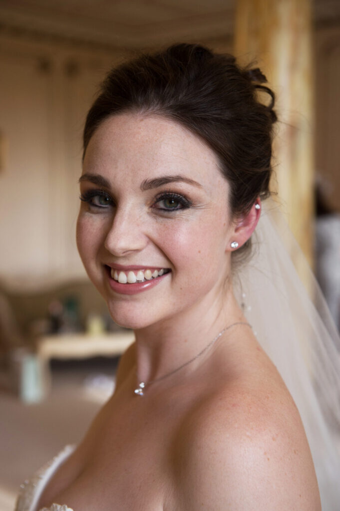 bride beaming following bridal prep, veil, pearl earrings, smiling, happy