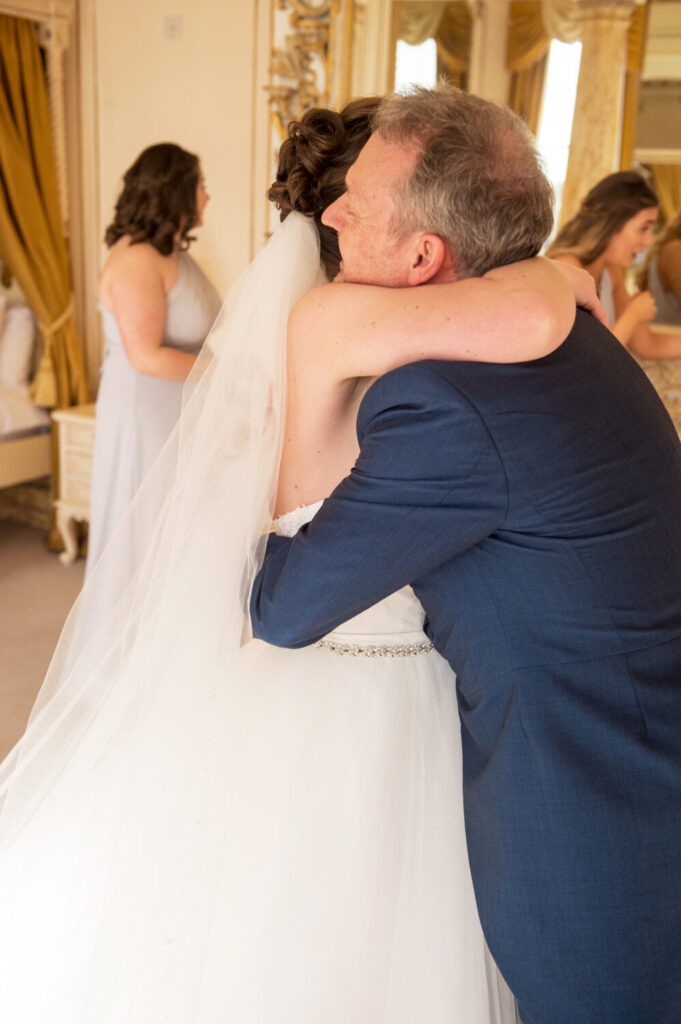 father of the bride embraces his daughter as she hugs him around her shoulder