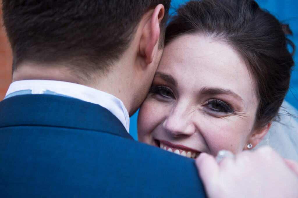bride, smiling over groom's shoulder, blue suit,