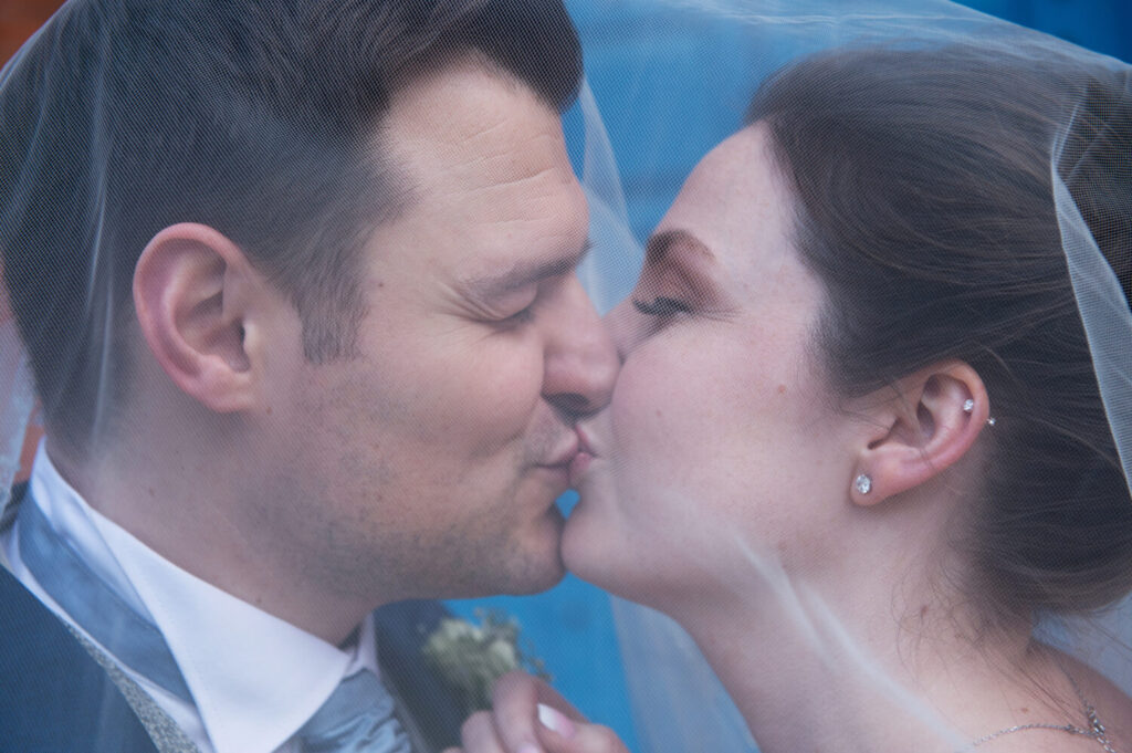 bride and groom close up shot, kissing under veil