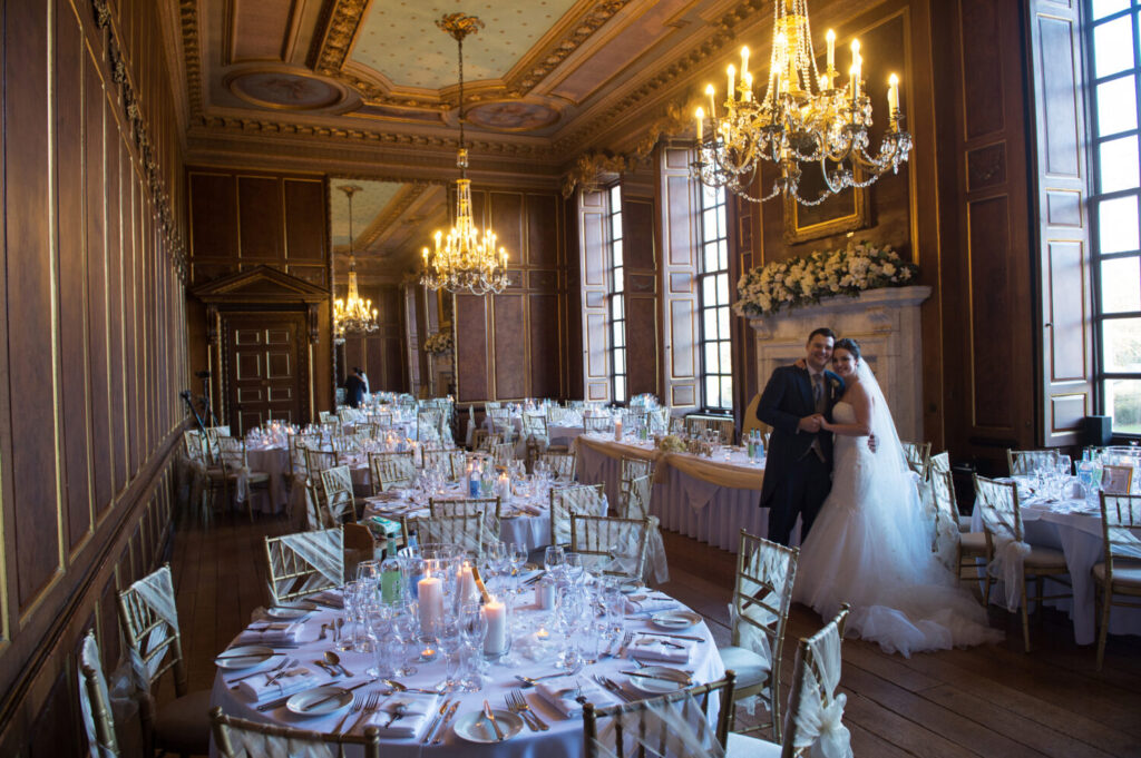 Grand Ballroom and Queen Charlotte’s Oak Panelled Gallery, wedding breakfast, chandeliers, large windows, huge fireplace, tables dressed for wedding breakfast