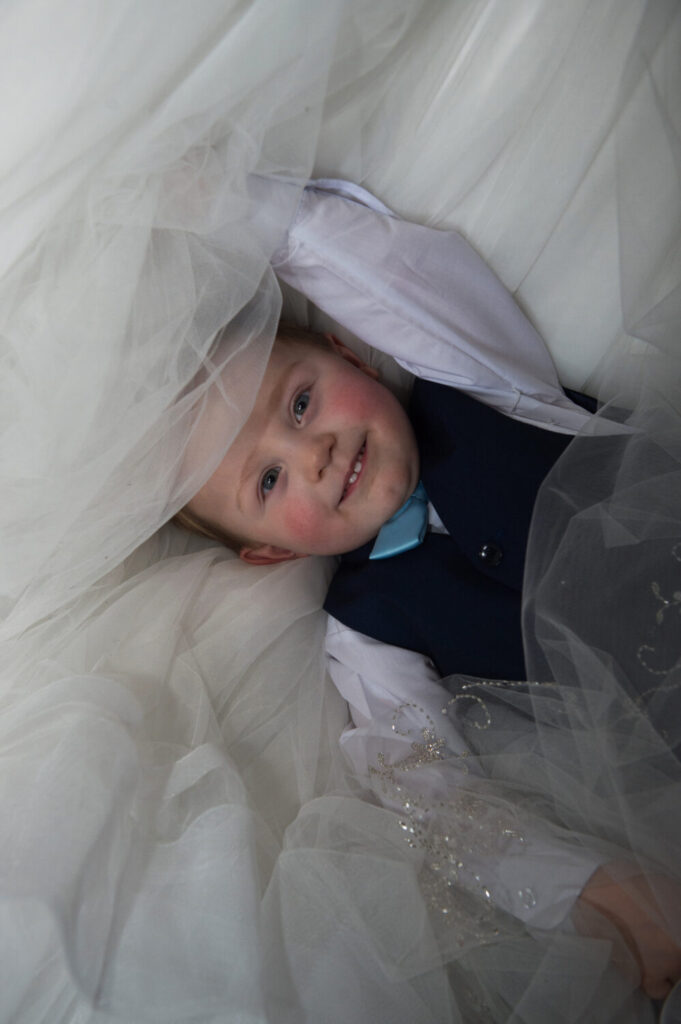 cheeky page boy peaks from under wedding dress