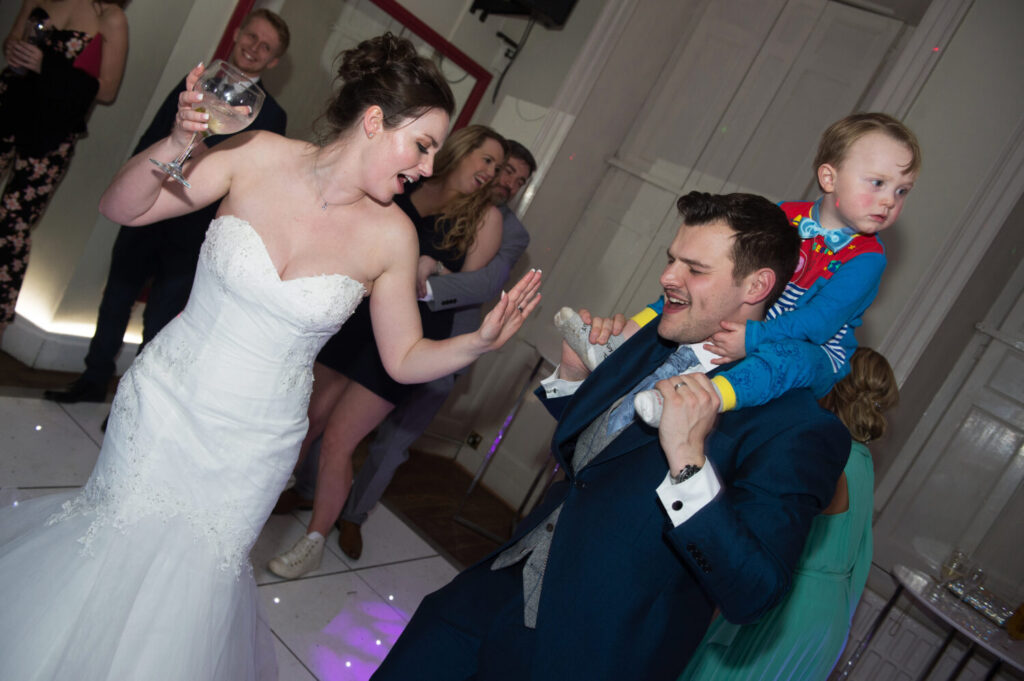 bride dances, groom dances with small page boy on his shoulders