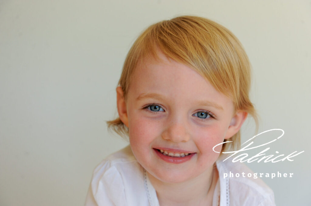 smiling girl toddler eye contact white blouse portrait studio